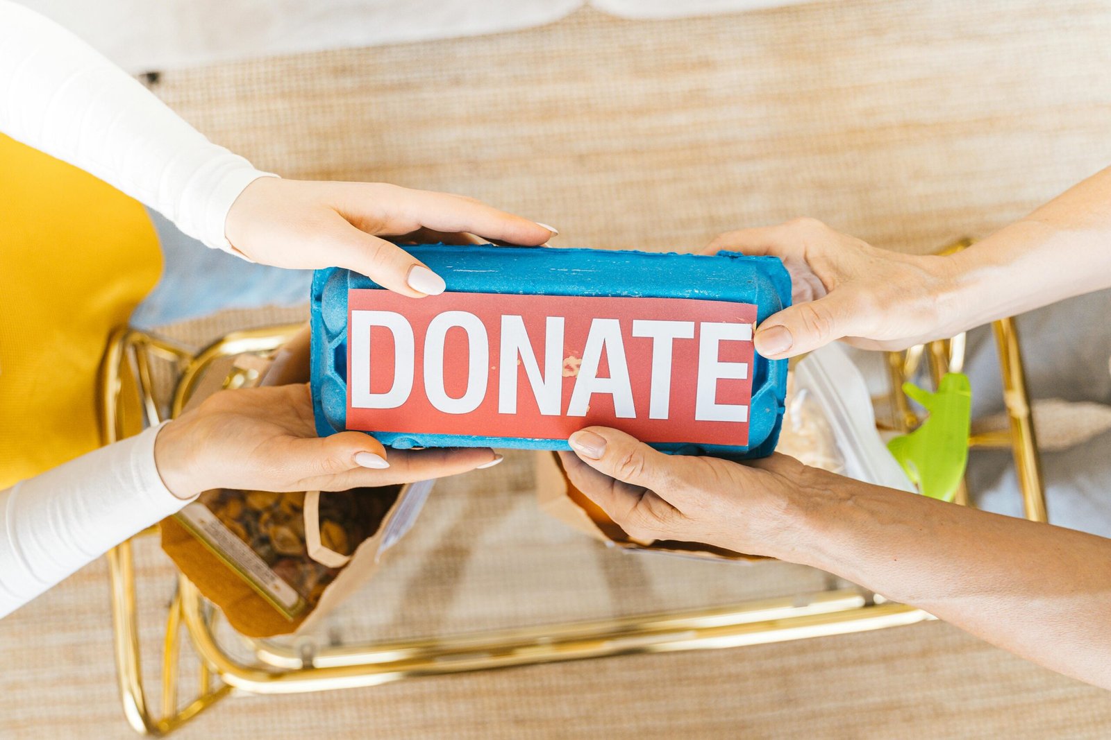 Hands exchanging a donation box filled with items, symbolizing giving and community support.
